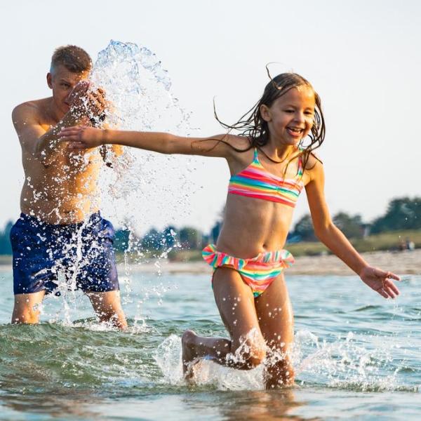 Vater und Kind amüsieren sich im Wasser am Saksild Strand im Küstenland