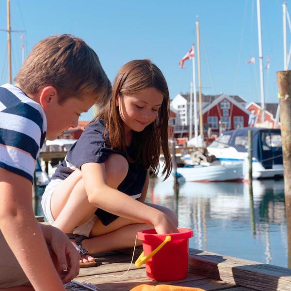 Kindern mitt ein rote Eimer an Juelsminde hafen