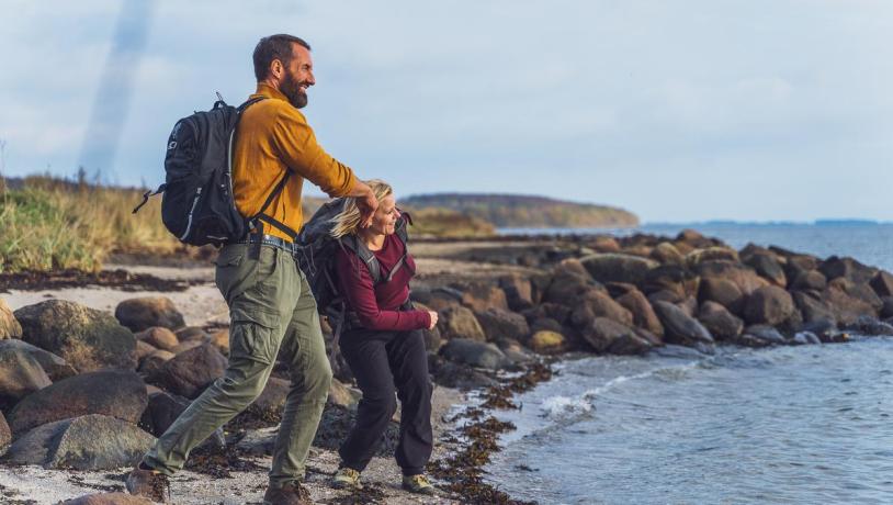 Zwei Wanderer lassen am Horsens Fjord Steine hüpfen