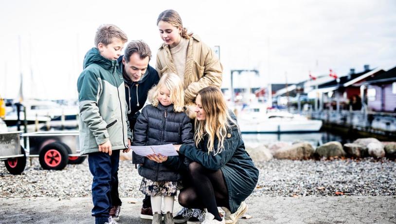 Familie schaut im Hafen von Juelsminde eine Schatzkarte an