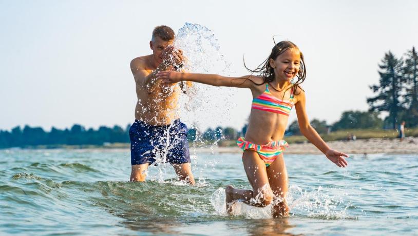 Vater und Kind amüsieren sich im Wasser am Saksild Strand im Küstenland