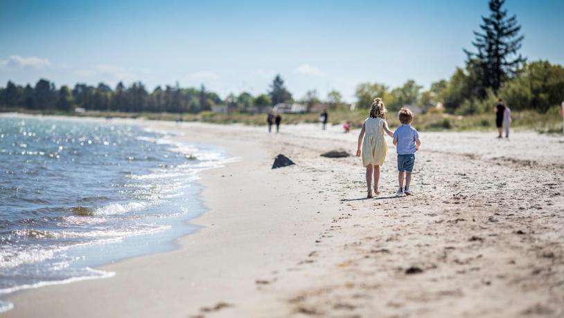 Kinder gehen bei Saksild über den Strand