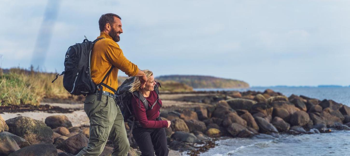 Zwei Wanderer lassen am Horsens Fjord Steine hüpfen