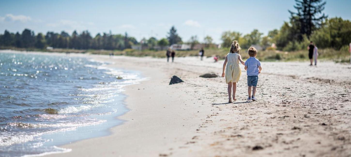 Kinder gehen bei Saksild über den Strand