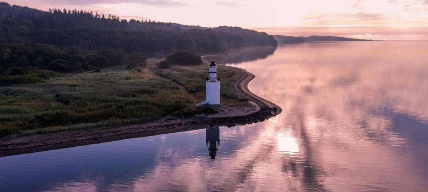 Ausblick auf Küste und Leuchtturm beim Hotel Vejlefjord im Küstenland