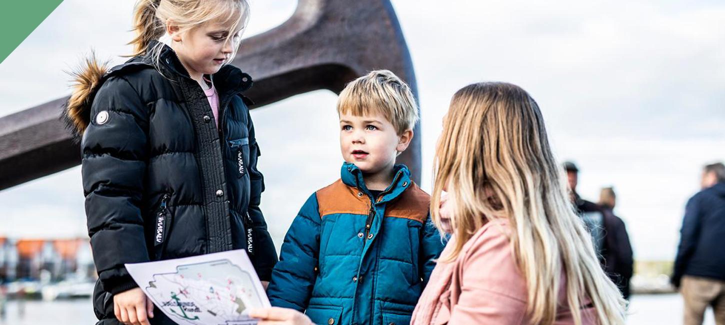 Mutter und zwei Kinder sehen vor dem Anker in Juelsminde auf die Schatzkarte
