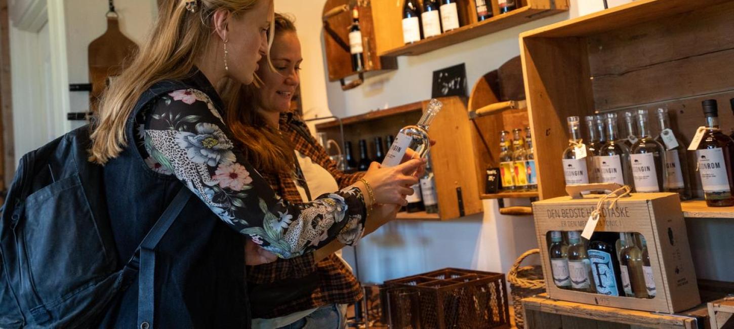 Zwei Frauen schauen sich im Kaufmannshof von Alrø in der Urlaubsregion Küstenland Delikatessen und Spirituosen an