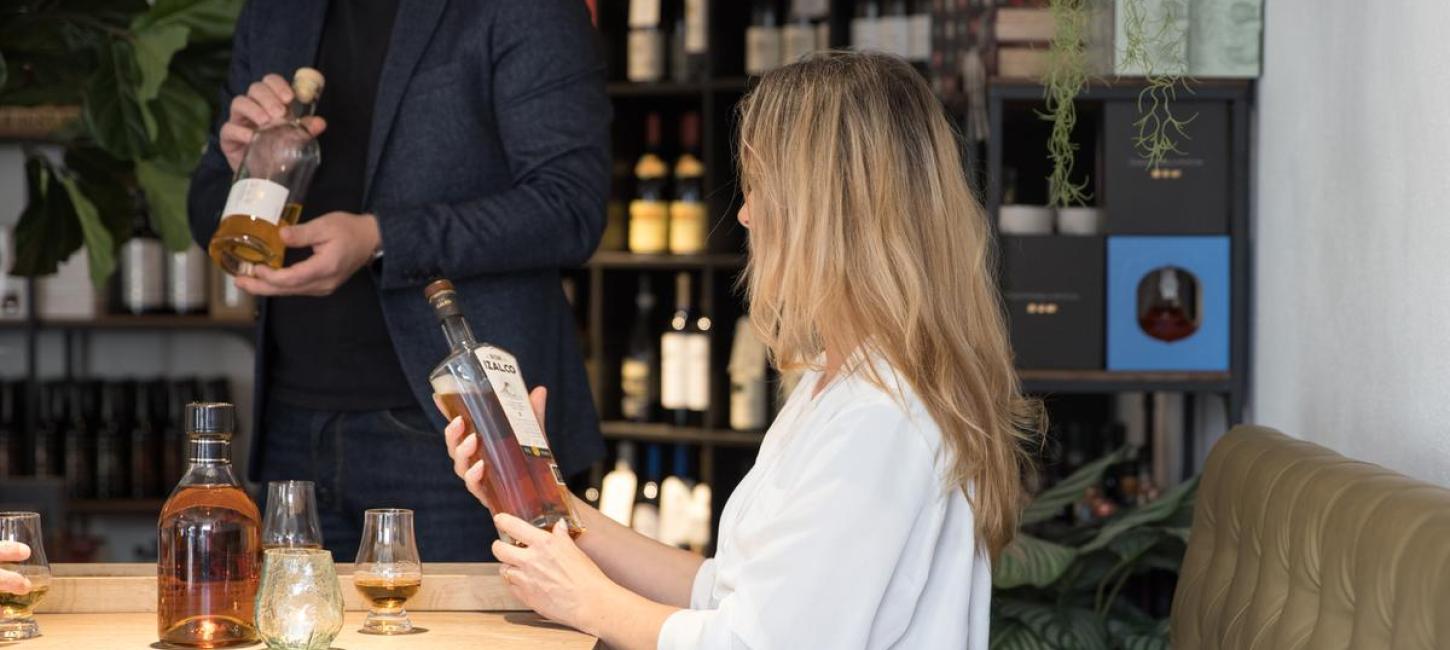 Frau hält eine Flasche Whisky beim Einzelhändler Water of Life auf dem Molkereiplatz in Brædstrup