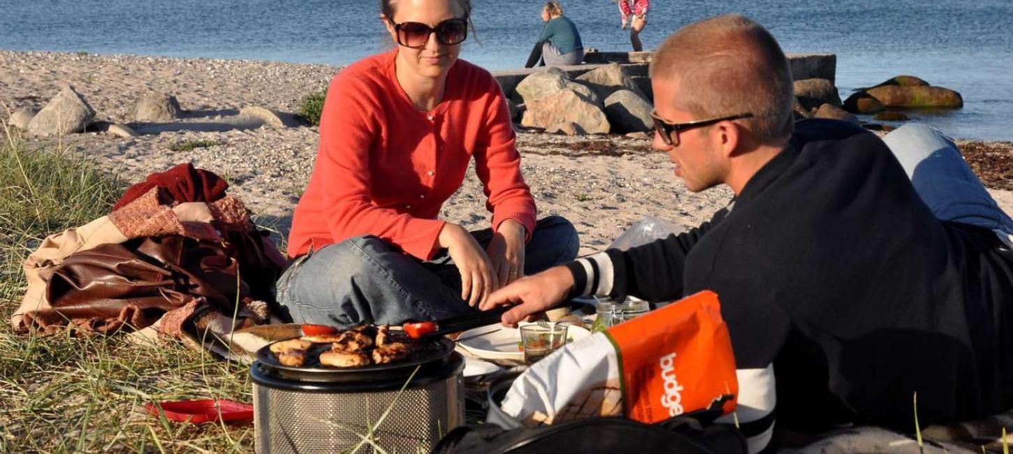 Familie macht es sich am Strand beim Ajstrup Camping gemütlich und grillt – ein Teil der Urlaubsregion Küstenland