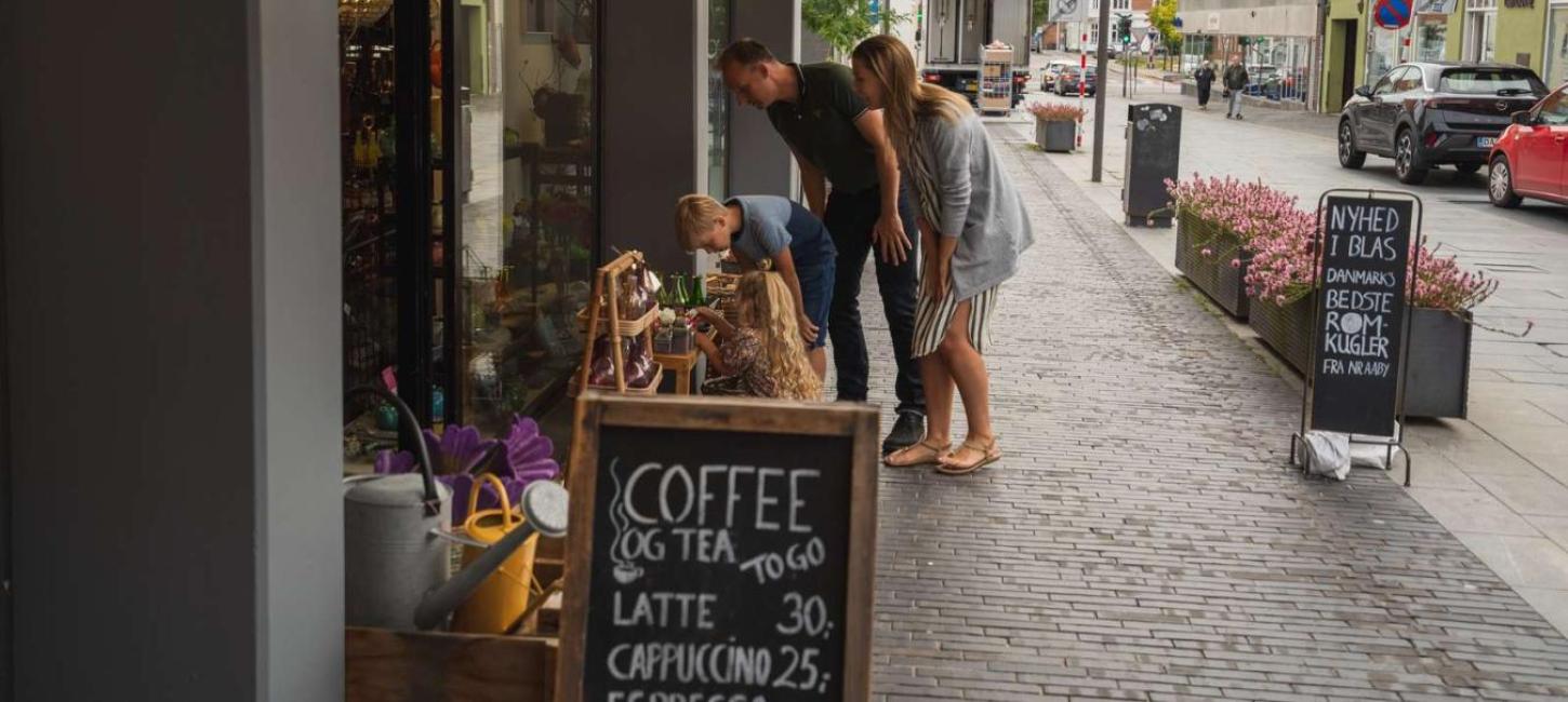 Familie beim Shopping schaut draußen vor einem Laden in Odder Ware an – ein Teil der Urlaubsregion Küstenland