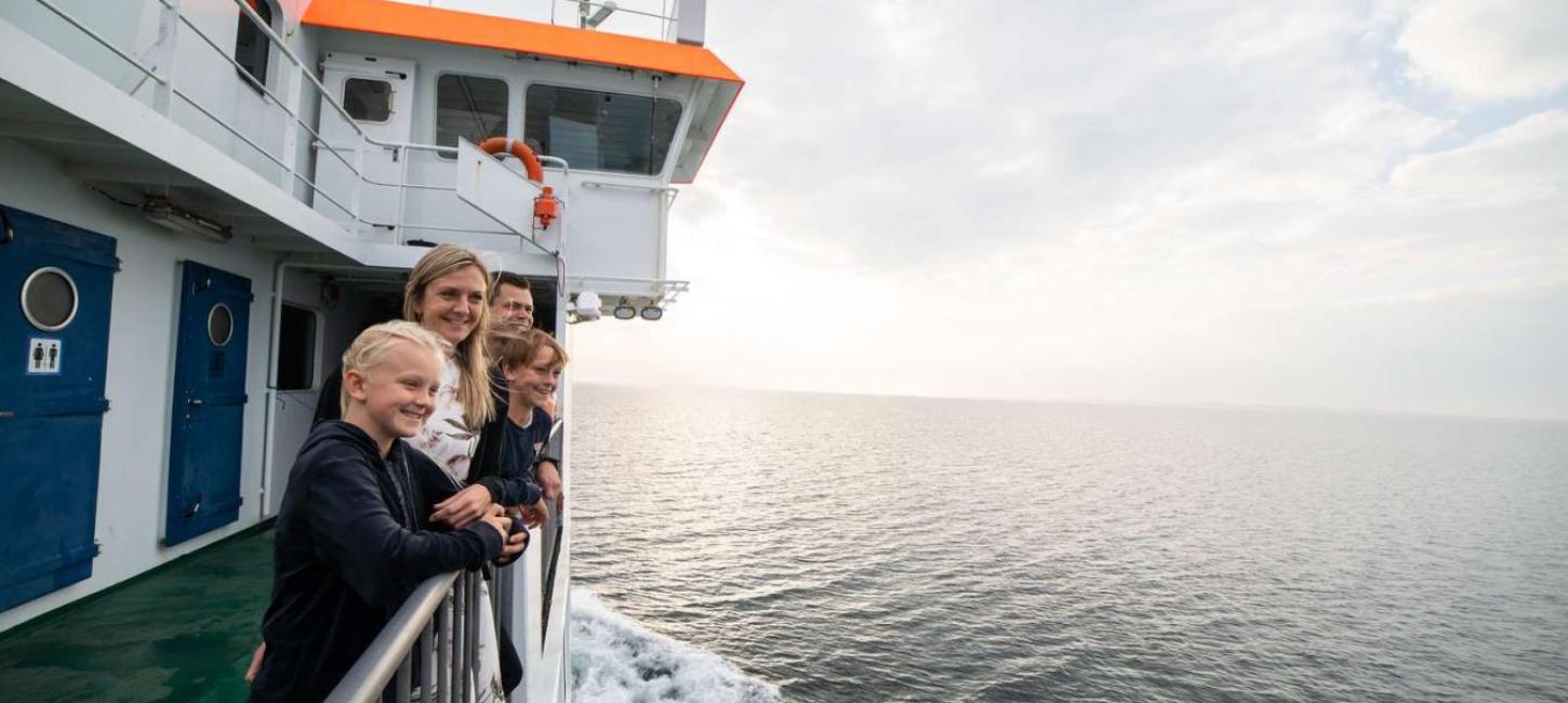 Familie an Deck schaut auf der Überfahrt von Snaptun nach Endelave mit der Endelave-Fähre übers Wasser