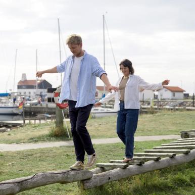 Mann und Frau balancieren auf dem Spielplatz im Hafen von Tunø – ein Teil der Urlaubsregion Küstenland