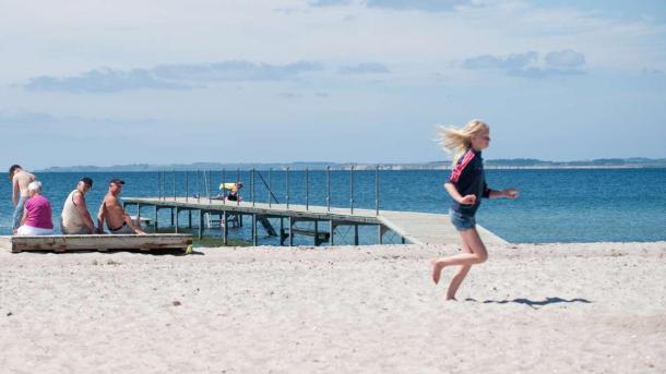 Mädchen läuft über den Hou Strand bei Hou Strand Camping, während die Großeltern im Hintergrund zuschauen