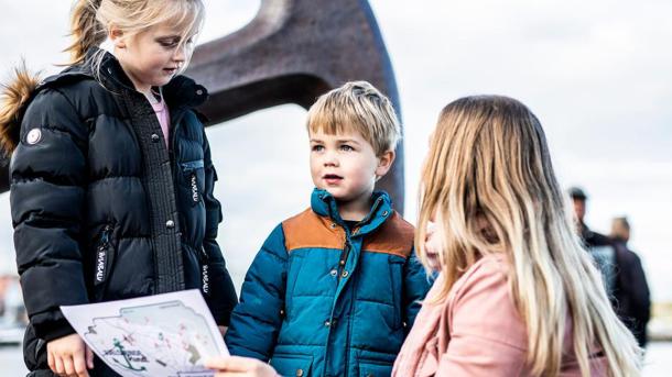 Mutter und zwei Kinder sehen vor dem Anker in Juelsminde auf die Schatzkarte