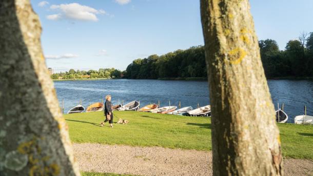 Frau geht mit ihrem Hund am See von Bygholm spazieren