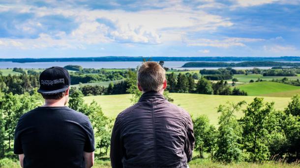 Zwei Jungen sitzen auf dem Aussichtshügel bei Trustrup und genießen die Aussicht