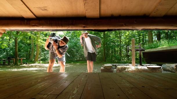 Zwei Freunde schauen in der Urlaubsregion Küstenland in einen Shelter hinein