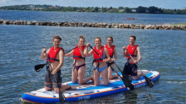 Fem unge menensker står på SUP-boards i Horsens Fjord