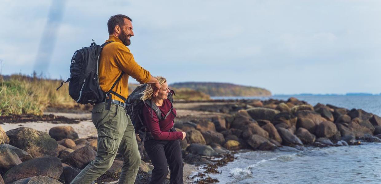 Zwei Wanderer lassen am Horsens Fjord Steine hüpfen