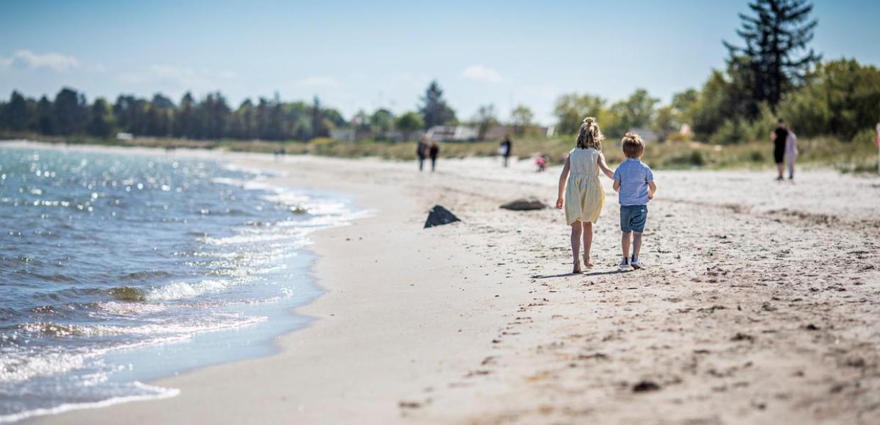 Kinder gehen bei Saksild über den Strand