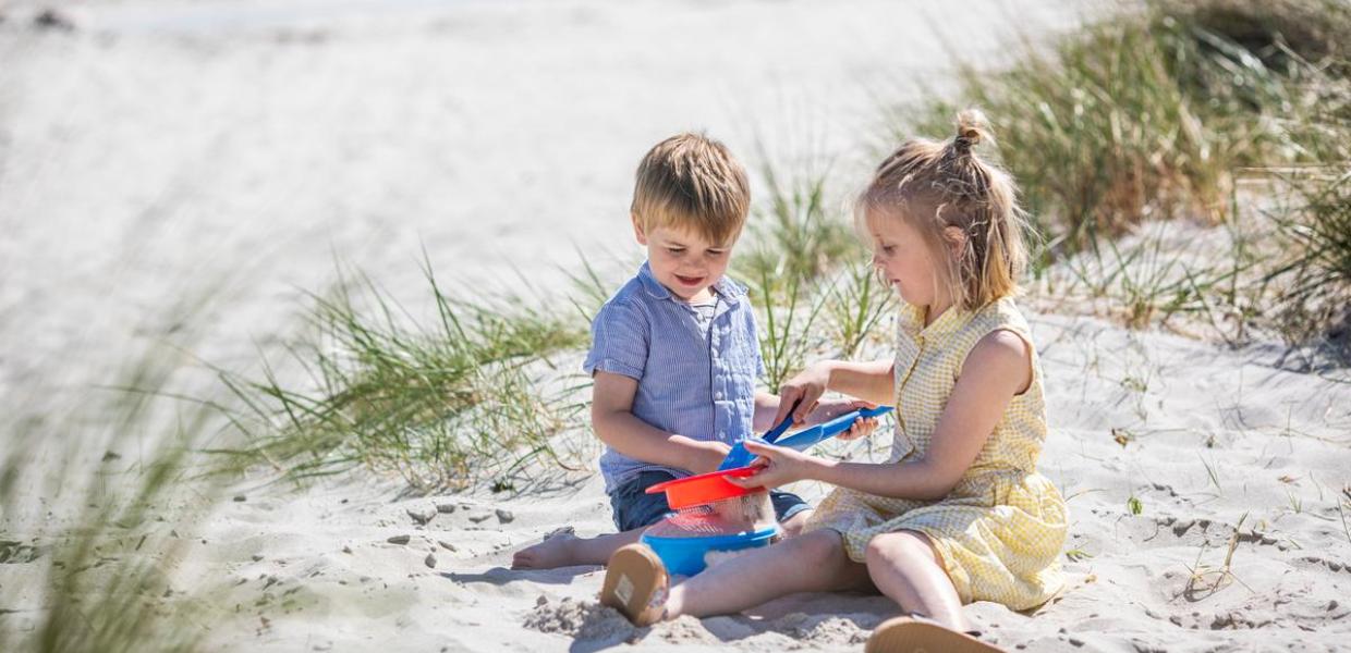 Kinder spielen auf dem Strand von Saksild