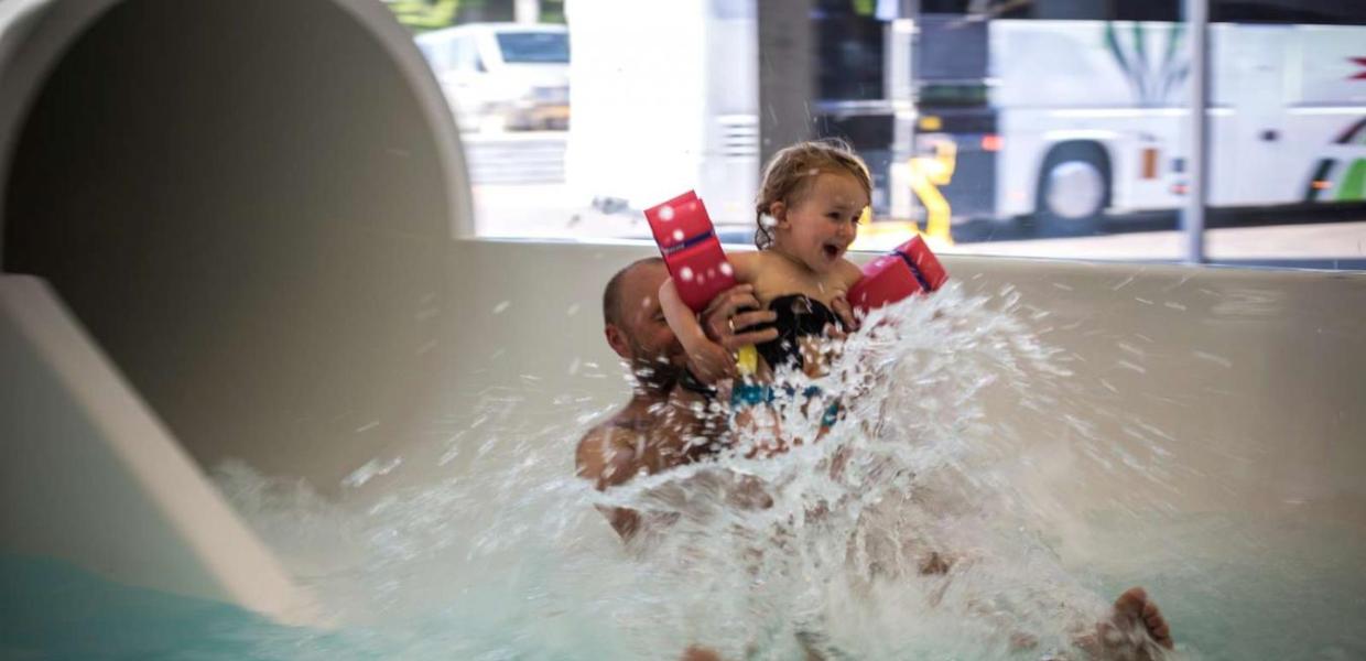 Vater und Tochter kommen in Vandhalla in Hou von der Wasserrutschbahn geflogen