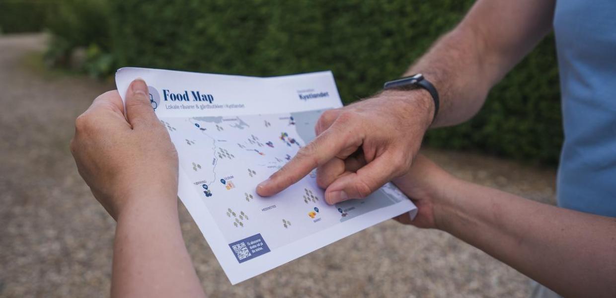 Et fødevarekort fra Destination kystlandet holdes ud i strakt arm 