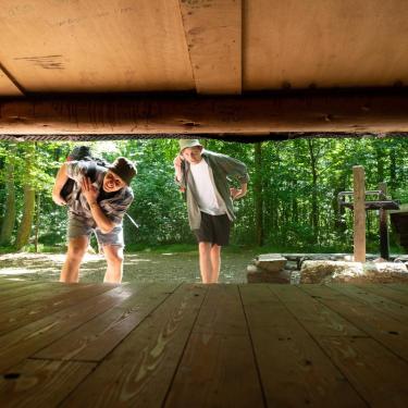 Zwei Freunde schauen in der Urlaubsregion Küstenland in einen Shelter hinein