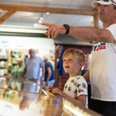 Junge und sein Vater schauen sich die Schiffsausstellung im Hafenmuseum in Juelsminde an