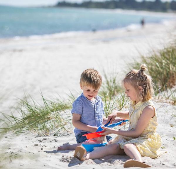 Kinder spielen auf dem Strand von Saksild