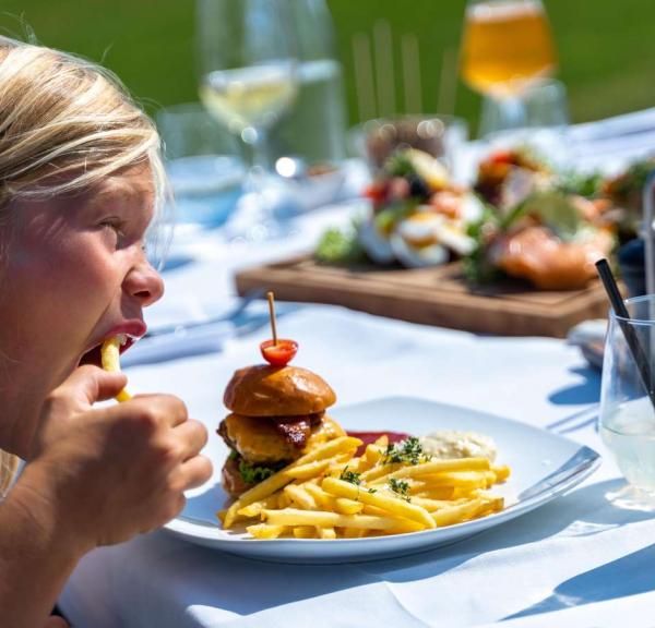 Junge isst Burger und Pommes Frites in der Molkerei auf Tunø, die sich in der Urlaubsregion Küstenland befindet