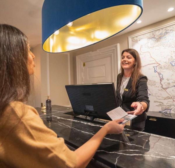 Frau checkt im Jørgensens Hotel ein, während die Rezeptionistin ihr die Schlüsselkarte reicht