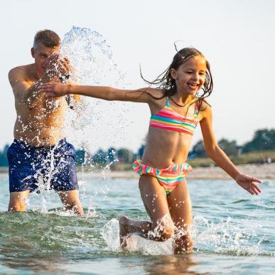 Vater und Kind amüsieren sich im Wasser am Saksild Strand im Küstenland