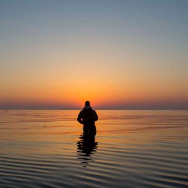 Mann angelt im Meer beim Sonnenaufgang