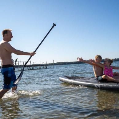 Kinder sitzen am Husodde Strand auf einem SUP-Board