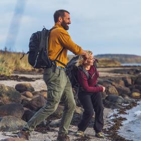 Zwei Wanderer lassen am Horsens Fjord Steine hüpfen