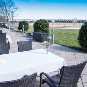 Freiluftterrasse mit Tisch und weißer Tischdecke und Stühlen beim Hotel Juelsminde 