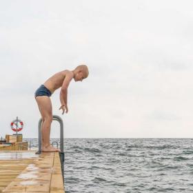 Junge steht auf dem Badesteg am Storstranden