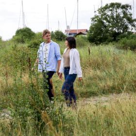 Paar geht Hände haltend auf einem Pfad zum Strand auf Tunø – ein Teil der Urlaubsregion Küstenland