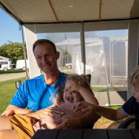 Vater mit zwei Kindern im Wohnwagenvorzelt beim Horsens City Camping – ein Teil der Urlaubsregion Küstenland