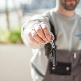 Mann hält bei einer Autovermietung Autoschlüssel in der Hand