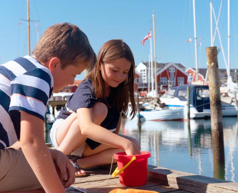 Kindern mitt ein rote Eimer an Juelsminde hafen